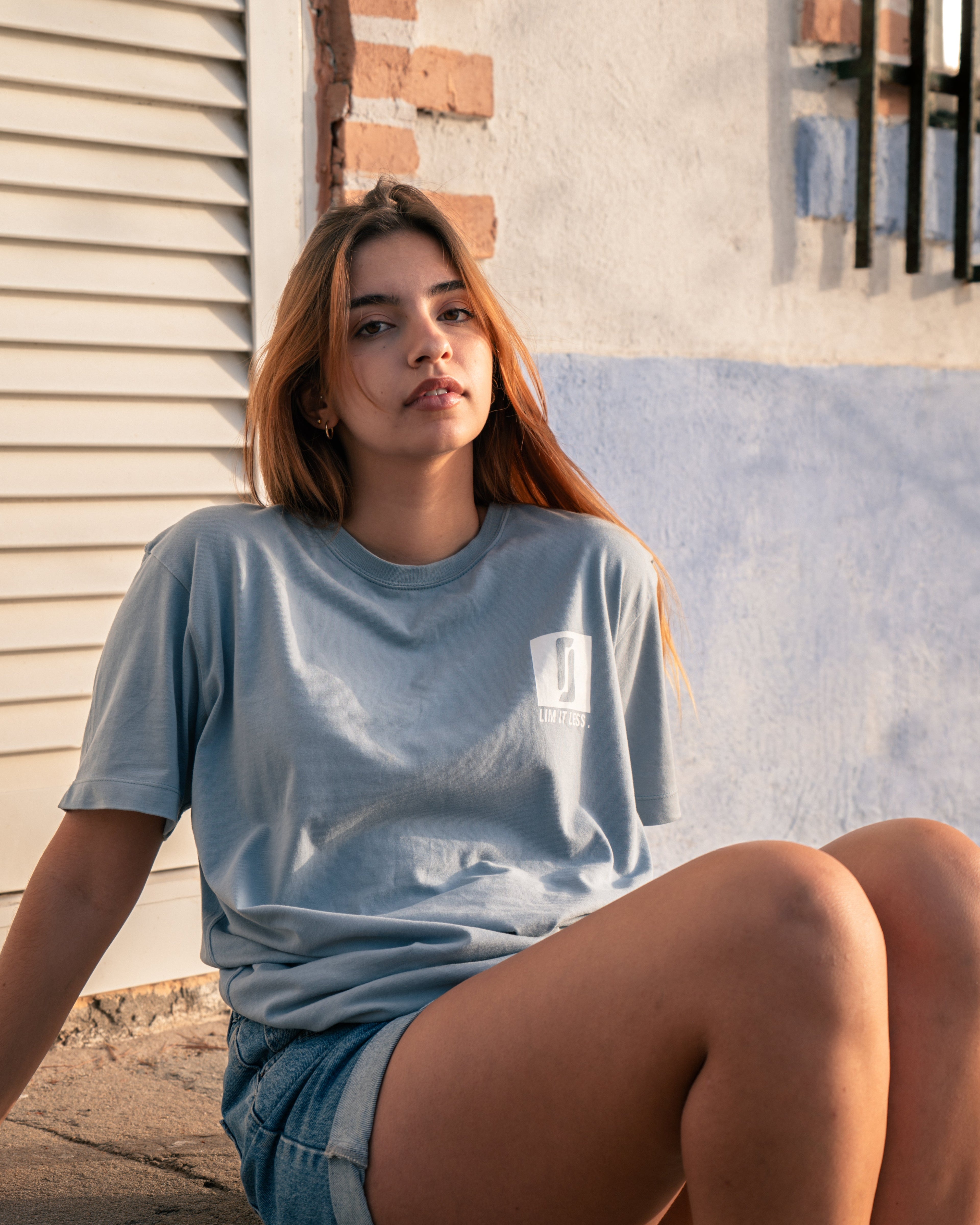 Modelo feminina com T-shirt Limitless Baía azul acinzentado em algodão premium, look descontraído urbano com calções de ganga, coleção Modern Royalty.